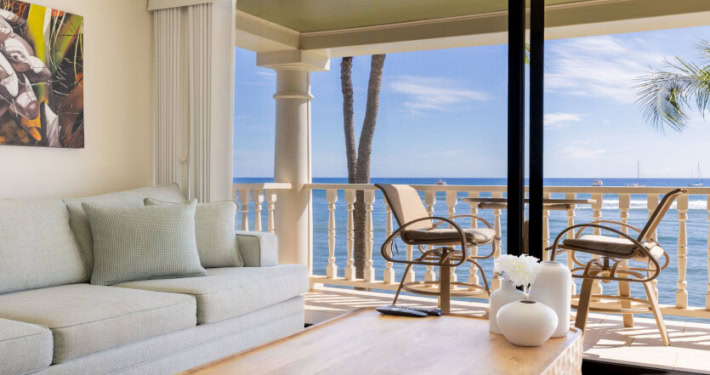 sofa and coffee table in the oceanfront unit looking out to private lanai with seating