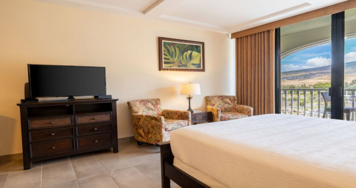 seating for two next to the sliding doors to the private lanai and flat screen television at the foot of the bed