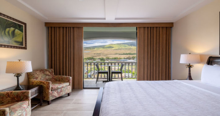 bedroom view looking out to the lanai and mountain range, seating and lamps