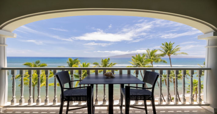 private lanai with seating and views of the ocean and palm trees