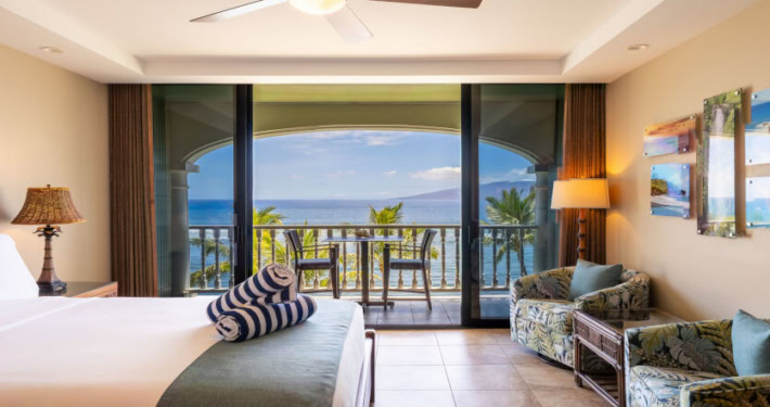 bed and separate seating with light fixtures near the sliding doors that lead to the private lanai